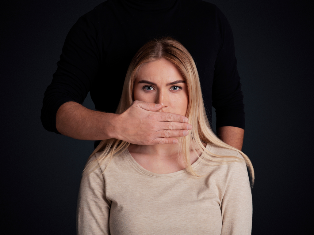 Eine Hand wird vor den Mund einer Frau gehalten