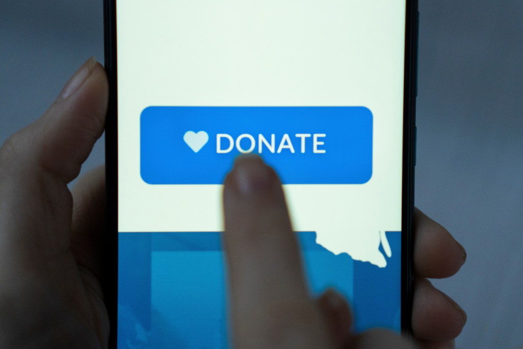 Ein Finger drückt auf einem Smartphone den Button Donate